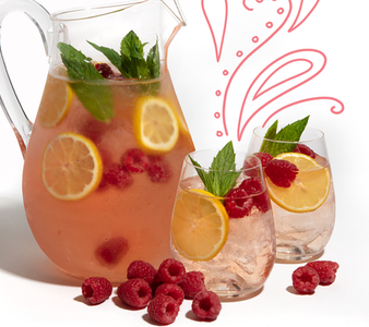 Ein Krug mit erfrischendem Getränk, gefüllt mit Zitronenscheiben, Himbeeren und frischer Minze, steht neben zwei Gläsern.